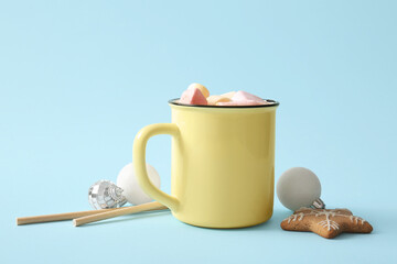 Cup of hot cocoa with marshmallows and cookie on blue background