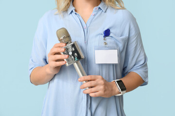 Female journalist with microphone on blue background, closeup