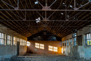 Old abandoned factory in the morning, morning light coming through the windows illuminating a brick...