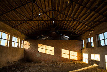 Old abandoned factory in the morning, morning light coming through the windows illuminating a brick wall