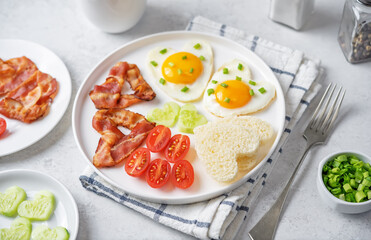 Fresh breakfast with fried eggs, fried bacon slices, bread slices and vegetables in the form of heart for Valentine's day holiday