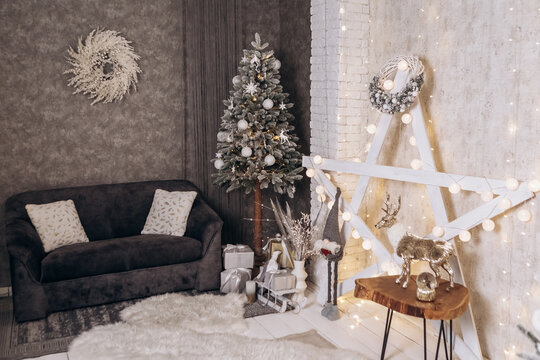 Cozy flat apartment photo studio room sled sleigh green Christmas Tree gifts presents garlands, candles decorated toys balls interior New Year lights glowing bokeh 