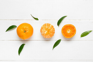 Sweet mandarins and leaves on white wooden background