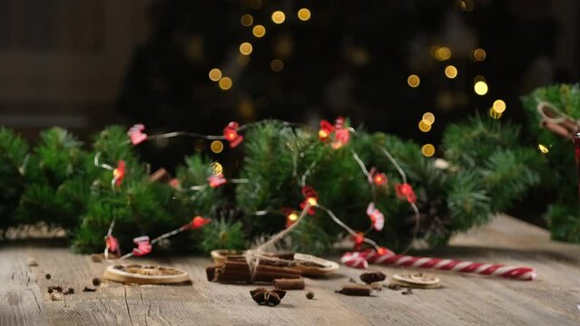Aromatic spices lying on wooden table in front of spruce branch and shining garland