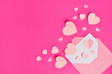 Composition with pink paper hearts and envelope on color background