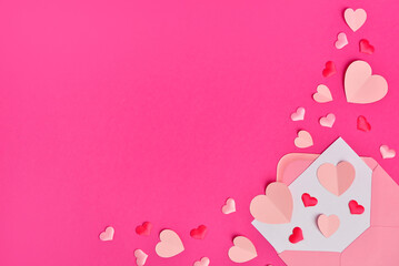 Composition with different paper hearts and envelope on pink background