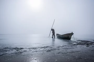 Fotobehang The story of a fisherman who wants to make a way for herself on a frozen lake on winter days and tries to get her fishing boat out of the ice.  © Ali
