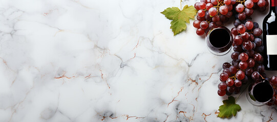 two glasses of red wine and a bottle surrounded by grapes on a marble white background