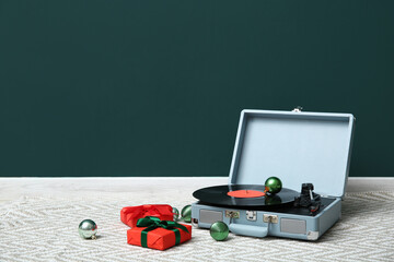 Vintage record player, Christmas gifts and balls on floor near color wall