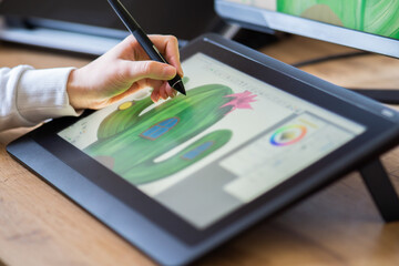 close up of a female hand drawing on a digital tablet. drawing on a digital drawing board. Graphic designer working from home