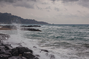 Ionian Sea coast in Giardini Naxos in the Metropolitan City of Messina on the island of Sicily, Italy. Taormina city on background
