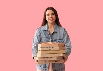 Young woman holding cardboard boxes with tasty pizzas on pink background