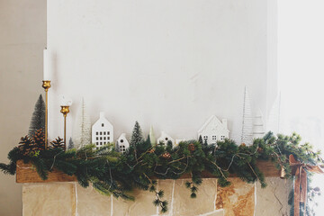 Stylish decorated christmas fireplace. Modern christmas trees, houses, pine cones and spruce...