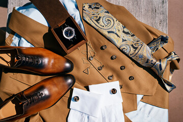 Brown leather shoes, a suit and a watch in a box lie on a wooden table - obrazy, fototapety, plakaty