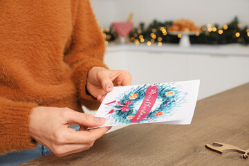 Obraz premium Mature woman with greeting card for Christmas celebration in kitchen