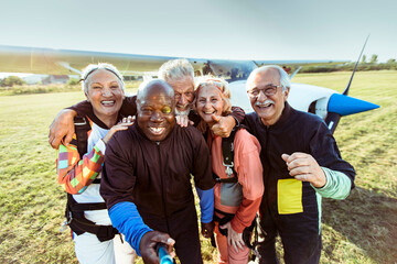 Group of joyful seniors take a selfie after their skydiving adventure