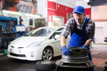 Professional american car mechanic changing the wheel at auto repair garage