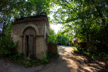 Abandoned checkpoint with a brick security booth surrounded by green thickets