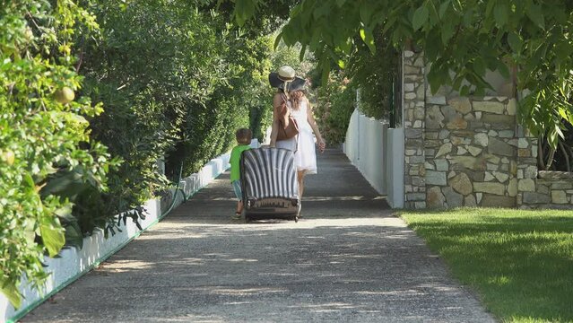 Mother rand son carry big suitcase on resort alley