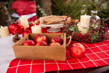Fototapeta na wymiar Christmas holiday table with open cranberry, cherry pie on red tablecloth with candles, advent wreath, apples. Flat lay is decorated with green spruce branches, berries of holly, eucalyptus. Homemade