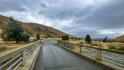 Flooded stream on the winding narrow gravel road between Lake Tekapo and Lake Pukaki in rural agricultural land