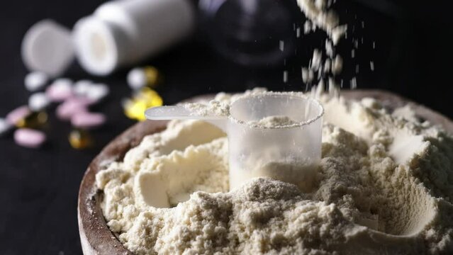 Pouring slow-motion whey dry sport protein from above, the food supplements enhance athletic performance