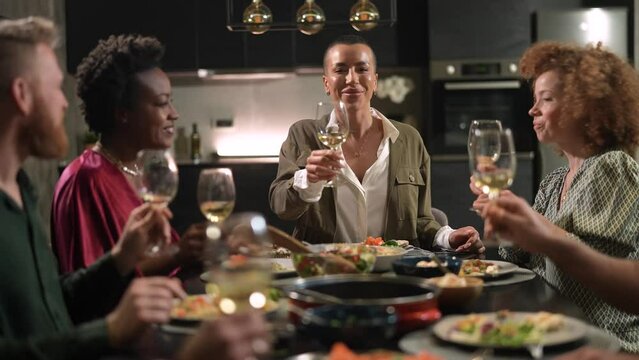 Young woman propose a toast during home dinner with friends