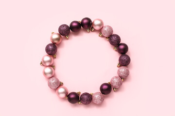 Frame made of Christmas tree balls on pink background