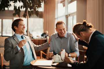Businessmen sitting in cafe together laughing