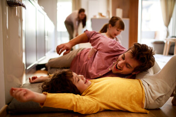 Obraz premium Happy young dad having fun with his kids on the floor at home