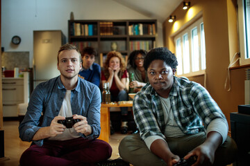 Young friends playing console video games at home