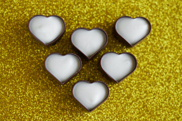 Obraz premium Unusual heart-shaped chocolates made of dark and white Belgian chocolate. Festive golden background for Valentine's Day. Photo. Bokeh. Selective focusing