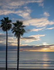 sunset over the ocean with person walking on beach