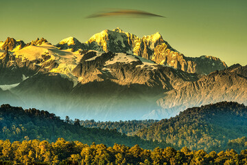 Layers of rain forest with Aoraki Mt Cook behind with lenticular cloud over the snow covered peak