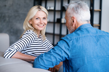Happy smiling woman sitting on couch at home and listen to husband