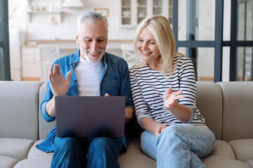 Happy mature couple communication with friends by video call on laptop