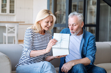 Excited mature man receive box with gift from his loving wife