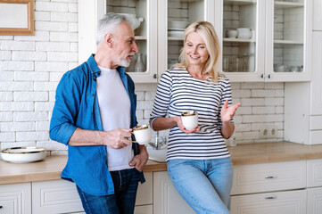 Mature couple enjoying morning coffee in modern kitchen