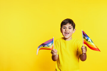 Cheerful boy in yellow waves 'Peace' rainbow flags, vibrant yellow background, symbolizing hope and...