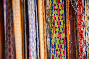 Many colorful belts with patterns. Folk art, handmade, Knitting of a traditional ethnic latvian folk belt - obrazy, fototapety, plakaty