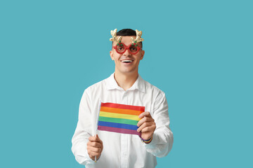 Young man in Christmas eyeglasses with LGBT flag on blue background