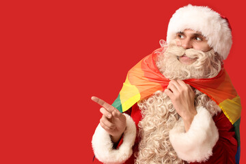 Obraz premium Santa Claus with LGBT flag pointing at something on red background