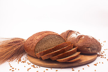 Photo of whole wheat breads, wheat ears and wheat grains and wooden container full of wheat on white background.