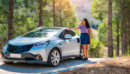 Electric car and EV electrical energy for environment, EV car on forest road with young woman in foreground