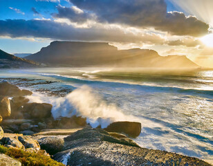 ocean breaks on shore of table mountain with sun rays