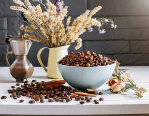 Roasted coffee beans in bowl on white kitchen table. and bouquet of dried flowers