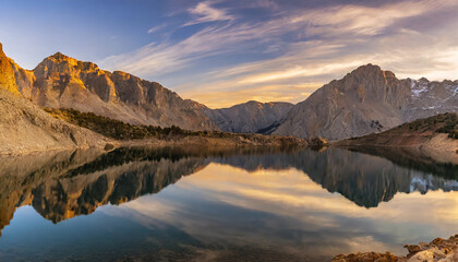 sunset in the mountains at a calm lake that creates a perfect reflection; beautiful scenery of rocky mountain