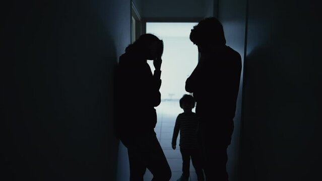 Silhouette of couple standing in corridor in crisis. Parents with child feeling worry and anxiety. Husband and wife discussing difficult situation