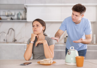 Obraz na płótnie Canvas Offended girl brushes aside guy words during argument in kitchen