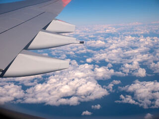 View from the window on the wing of the plane and passing snow-white clouds.